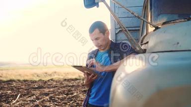 智慧农业。 男子农民司机站在卡车附近的数字平板电脑。 慢动作视频。 肖像商人